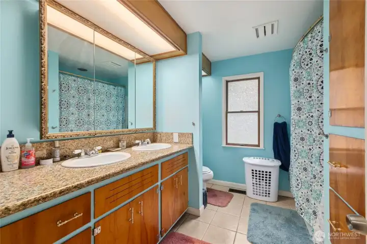 The main-floor bathroom features classic tile flooring, a full tub/shower, and a double vanity—combining timeless style with practical functionality for everyday use.