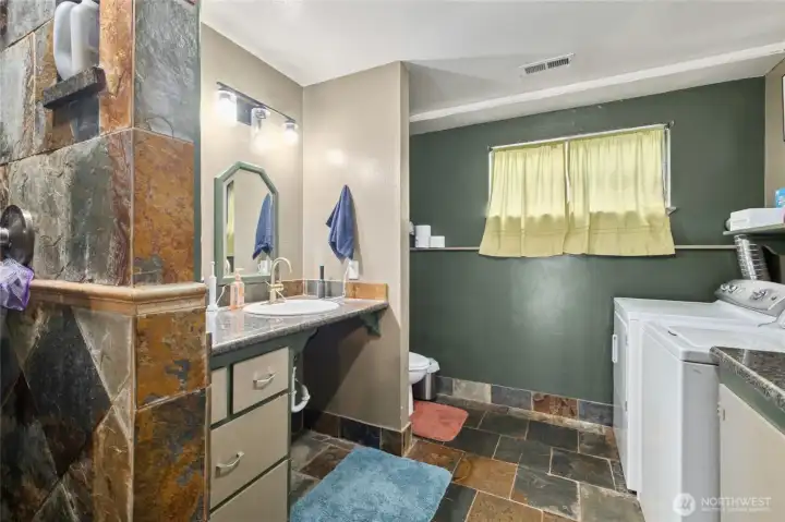 The lower-level bathroom features a stylish tile shower and plenty of laundry space, combining functionality with everyday convenience.