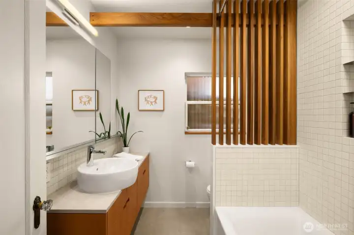 The fully updated bath features wood accents, stone tile, electical for a bidet, and a large skylight.