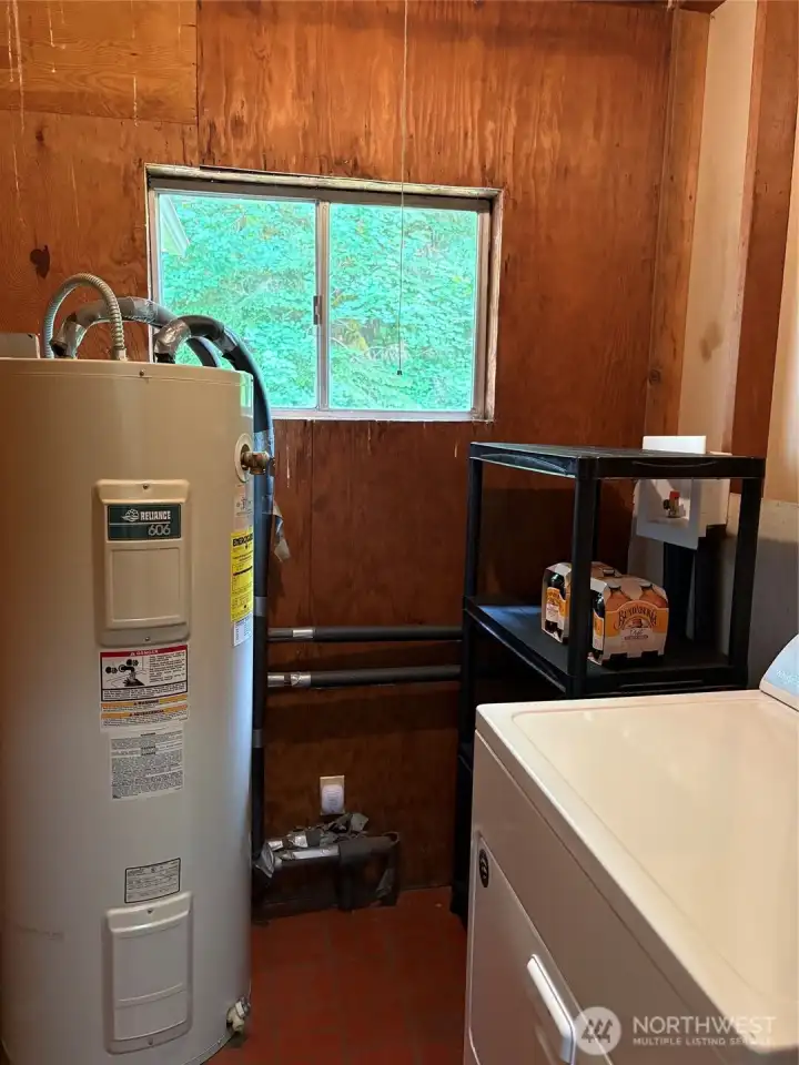 Utility room with electric hot water heater and dryer.