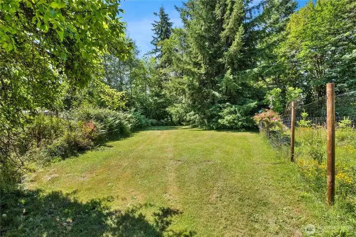 The second fenced garden plus large grassy area that leads to creek trail.