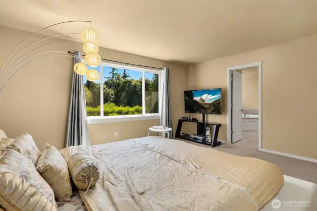 Luxurious primary bedroom with views of the backyard.