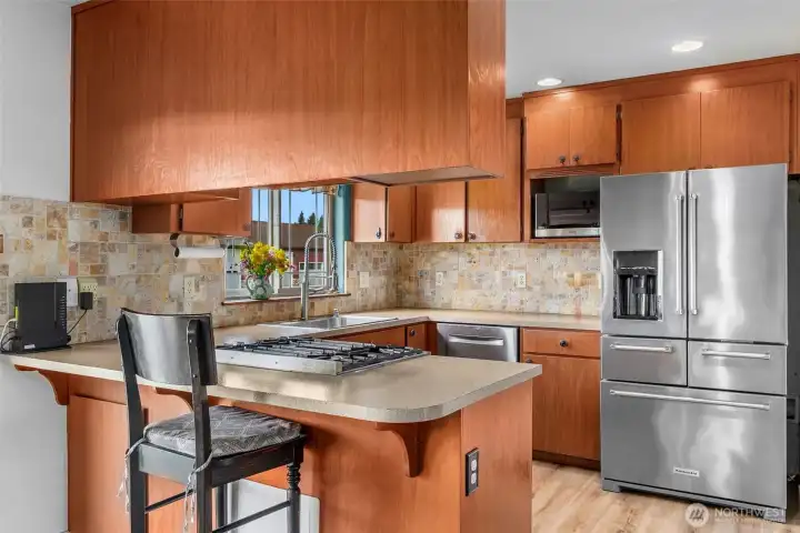 Kitchen has tall backsplash in pretty muted colors. Kitchen counter extends out for an eating bar allowing for up to three chairs. Kitchen will come with all appliances.
