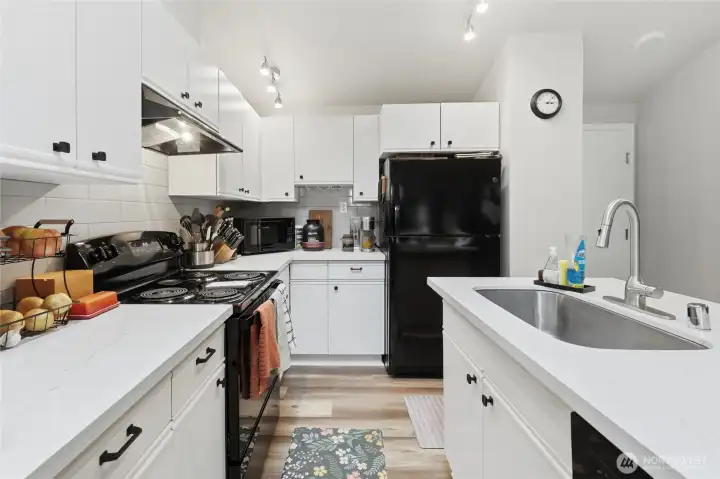 Undermount sink, quartz countertops, tiled backsplash, plenty of cabinets and counterspace.  There is also a dishwasher, not shown in the picture. Door on the right go to your 2-car garage.