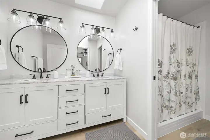 Remodeled primary bathroom with freestanding marble-top dual sink vanity and skylight Remodeled primary bathroom with freestanding marble-top dual sink vanity and skylight