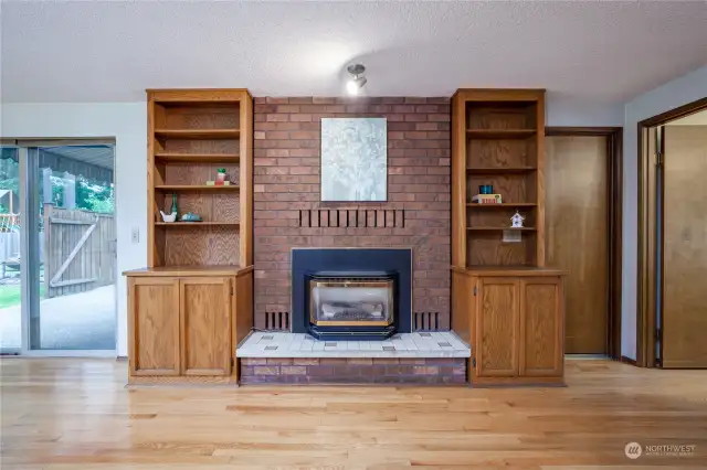 Gas fireplace with brick surround and built-in cabinetry with display shelves