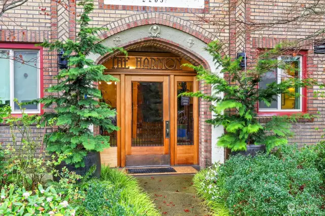 Impressive entrance  with arched entry,  wood and glass door, surrounded by lush landscaping