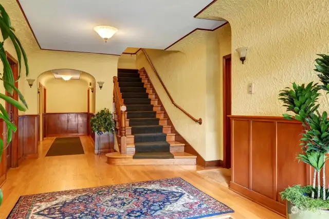 Welcoming entrance with warm wood flooring and rich paneled walls