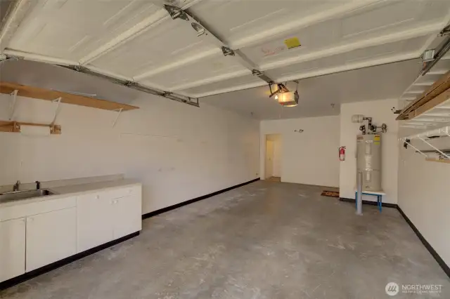 Extra large 1 car garage with storage and a convenient sink with built-in cabinetry.