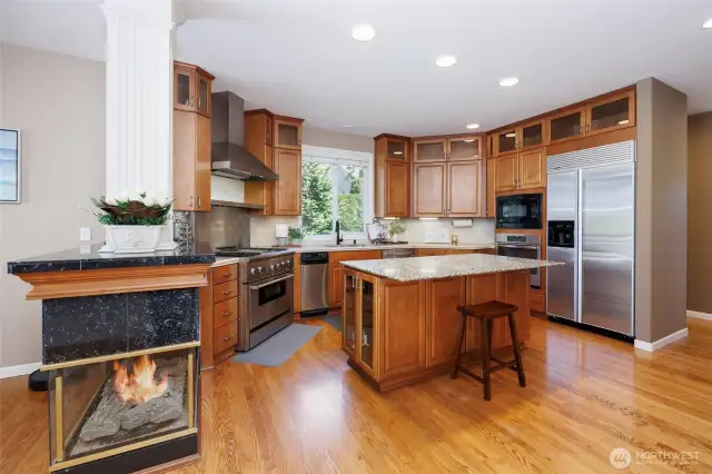 Chef's kitchen features a double-sided gas fireplace, walk-in pantry & tons of storage.