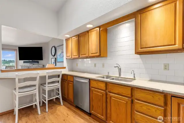 Kitchen with loads of counter space, cabinetry and convenient bar with views to the water across the living room
