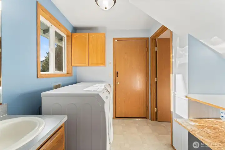 Bright laundry room complete with storage cabinetry and exterior window for ventilation and natural light.