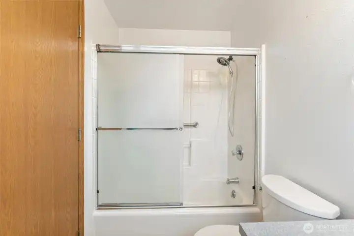 Clean and well-maintained shower/tub combination with sliding glass doors and tile surround. Practical design perfect for everyday convenience.