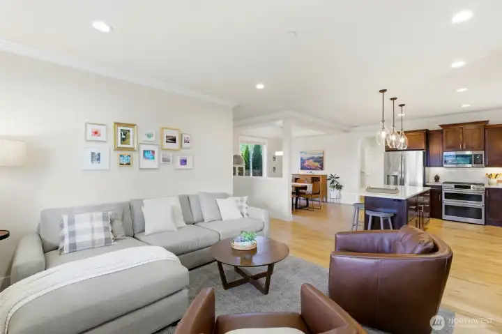 Open-concept great room with site-finished hardwoods, crown molding, and seamless flow into the chef's kitchen — bright, light-filled, and built for entertaining. Open-concept great room with site-finished hardwoods, crown molding, and seamless flow into the chef's kitchen — bright, light-filled, and built for entertaining.