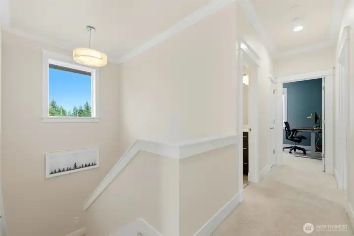 Light-filled upstairs hallway with crown molding leading to four bedrooms and dedicated home office. Light-filled upstairs hallway with crown molding leading to four bedrooms and dedicated home office.