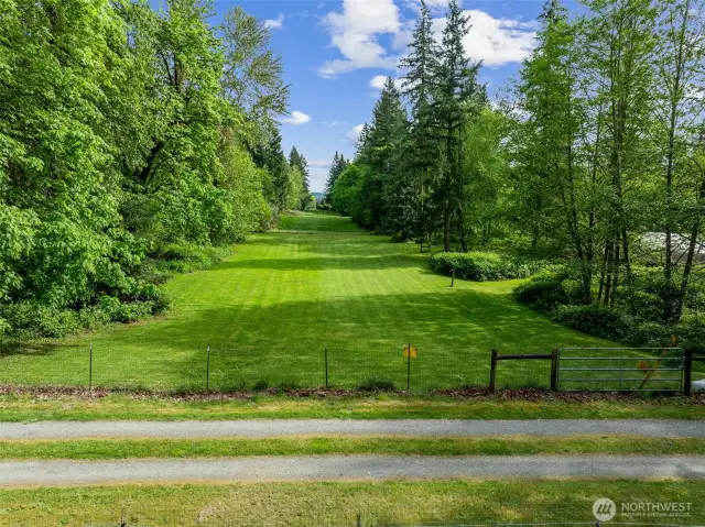 Behind the stables is this beautiful pasture ready for your horses! It extends from fence to fence pictured here.