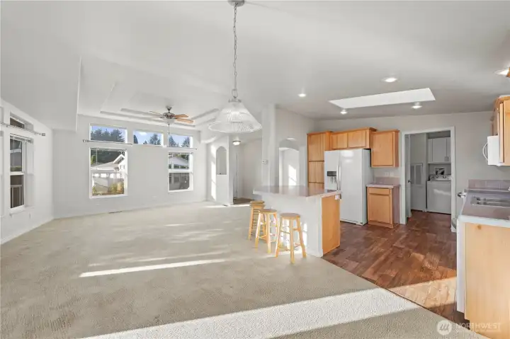 Spotlessly maintained great room with open-concept living and dining, filled with natural light from large windows and a skylight.