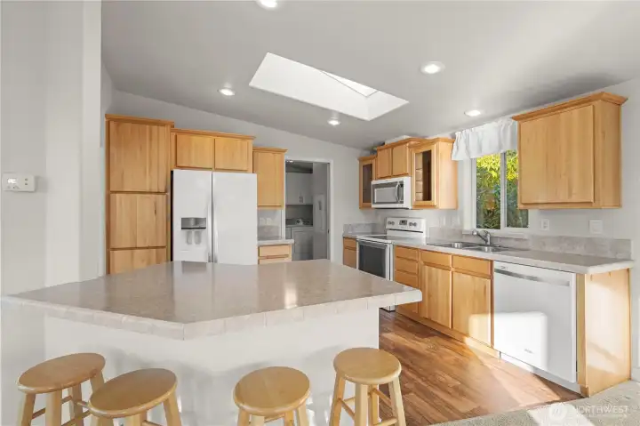 The kitchen features warm wood cabinetry, ample counter space, and a convenient breakfast bar with seating.