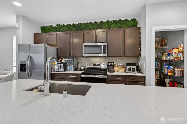 Well-appointed kitchen with stainless steel refrigerator, upper cabinetry, and abundant storage