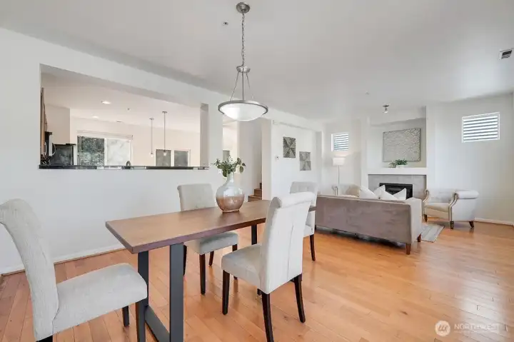 Open-concept living and dining area offers a bright, cohesive flow that brings the entire main level together. The dining space sits comfortably between the kitchen and living room, creating an effortless connection for everyday living and entertaining. Warm natural light fills the room through multiple windows, highlighting the contemporary finishes, inviting fireplace, and clean, modern design. It’s a beautifully integrated space that feels both spacious and welcoming.