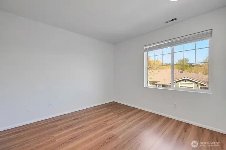 Bedroom 3 offers a bright and versatile space with fresh finishes and warm natural light. A large window frames neighborhood and treetop views, creating an inviting atmosphere for use as a bedroom, guest room, or home office. Clean lines and a modern palette make it an easy space to personalize.