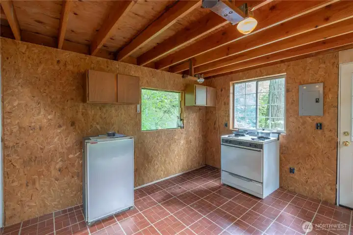 Another view of the kitchen area. Propane run stove, window above stove looks out to the entrance. Front door to the right.