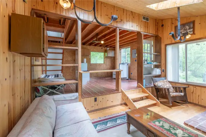 A view looking from living room into the kitchen area. Lots of natural wood trim.