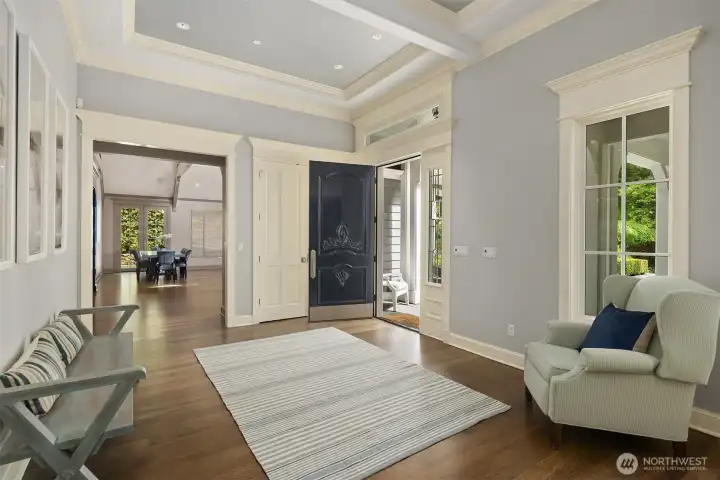 A grand entry sets a sophisticated tone with its soaring custom tray ceiling, detailed crown molding, and beautiful hardwood floors. The handsome front door with expansive sidelights fills the entire foyer with bright, welcoming light. A grand entry sets a sophisticated tone with its soaring custom tray ceiling, detailed crown molding, and beautiful hardwood floors. The handsome front door with expansive sidelights fills the entire foyer with bright, welcoming light.