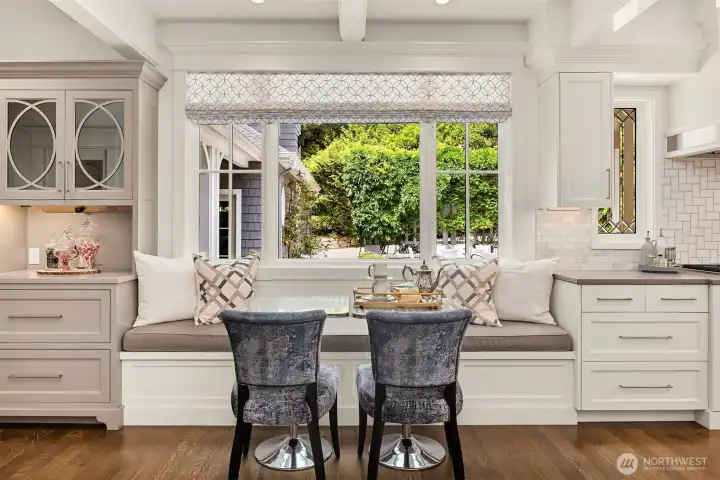 Bright kitchen eating space featuring custom built-in bench seating with ample room for 6 to 8 guests. The expansive garden window frames serene outlooks to the private backyard patio and lush, mature landscaping. Bright kitchen eating space featuring custom built-in bench seating with ample room for 6 to 8 guests. The expansive garden window frames serene outlooks to the private backyard patio and lush, mature landscaping.