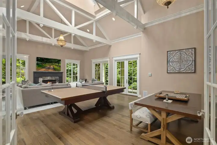 This expansive family room is the ultimate casual entertaining hub, offering generous square footage easily accommodating a large media setup for watching sporting events, a ping pong table, and a casual dining area. The space is anchored by a cozy wood-burning fireplace and features custom built-in bench seating, while multiple sets of classic French doors open to the outdoor patio for a seamless indoor-outdoor lifestyle. This expansive family room is the ultimate casual entertaining hub, offering generous square footage easily accommodating a large media setup for watching sporting events, a ping pong table, and a casual dining area. The space is anchored by a cozy wood-burning fireplace and features custom built-in bench seating, while multiple sets of classic French doors open to the outdoor patio for a seamless indoor-outdoor lifestyle.
