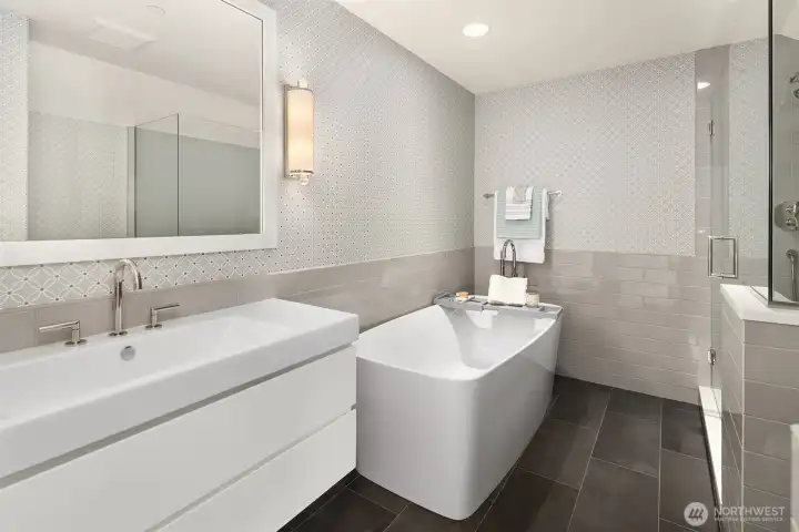 This beautifully designed upstairs full bathroom offers a luxurious, spa-like experience with premium finishes. The space features a sleek, modern freestanding soaking tub alongside a separate glass-enclosed walk-in shower. A wide floating vanity with custom spacious sink and striking tile accents completes this bright and functional retreat. This beautifully designed upstairs full bathroom offers a luxurious, spa-like experience with premium finishes. The space features a sleek, modern freestanding soaking tub alongside a separate glass-enclosed walk-in shower. A wide floating vanity with custom spacious sink and striking tile accents completes this bright and functional retreat.