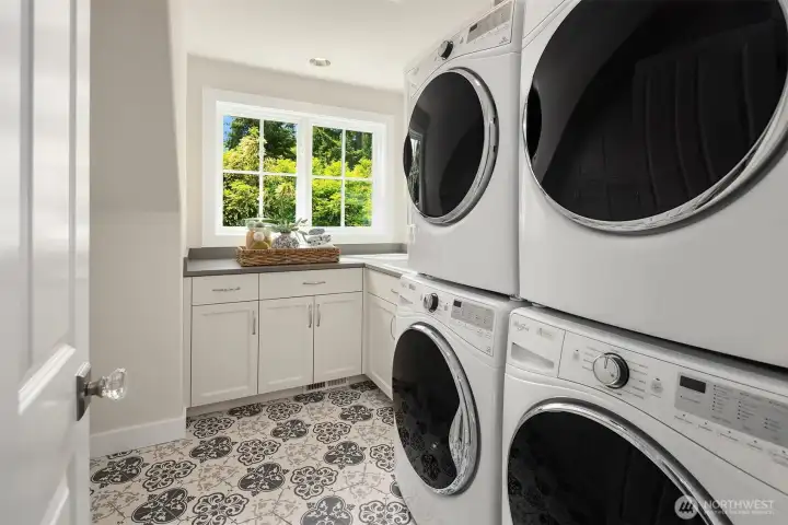 Ultra-convenient upstairs laundry room featuring a high-capacity dual setup with two sets of washing machines and dryers. Complete with bright windows and built-in cabinetry. Ultra-convenient upstairs laundry room featuring a high-capacity dual setup with two sets of washing machines and dryers. Complete with bright windows and built-in cabinetry.