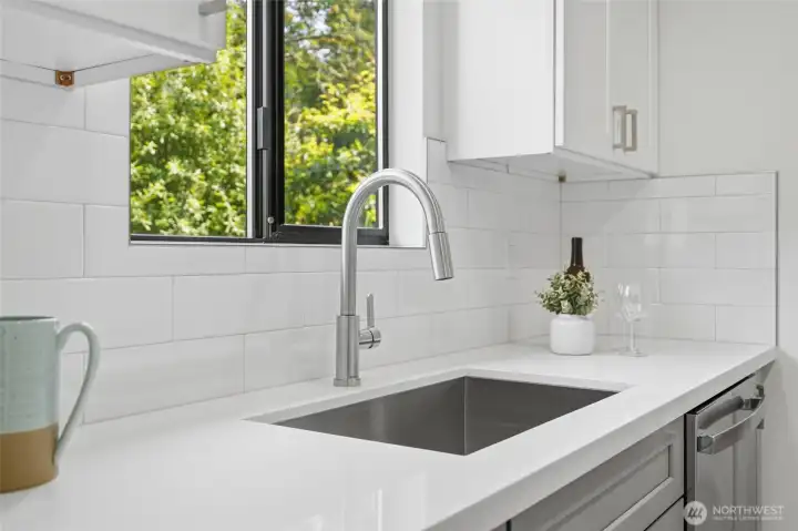 The kitchen sink and tile backsplash and view windows above.