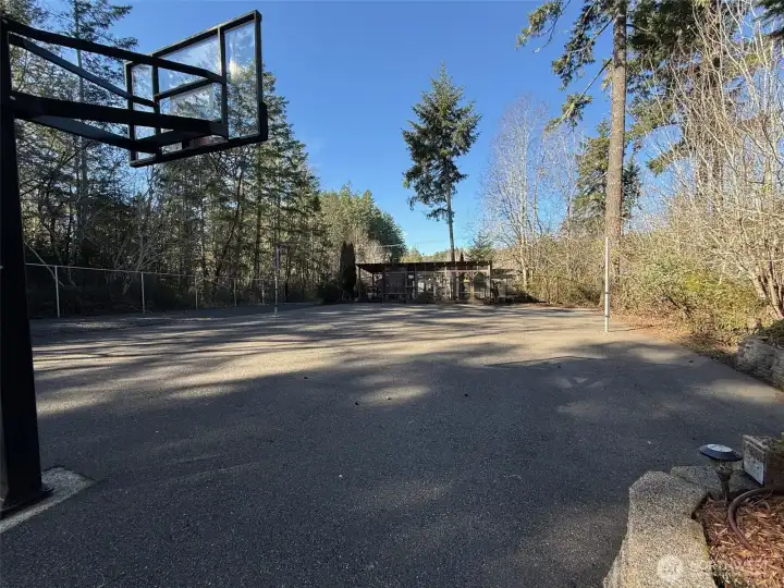 Once through the gate you see the large sport court, with adjacent covered outdoor seating for all of your spectators.  Complete with a pickleball net, and basketball hoop. At each end of the court is a chicken coop. One for the baby chicks and one for the adults.