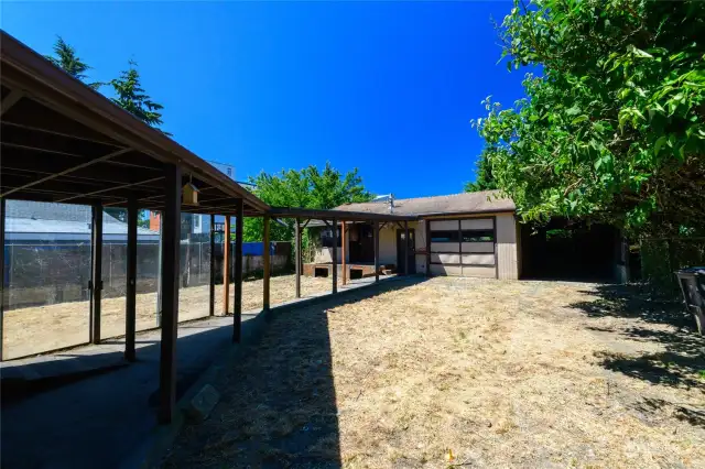 View of the garage, carport and yard from the gate.
