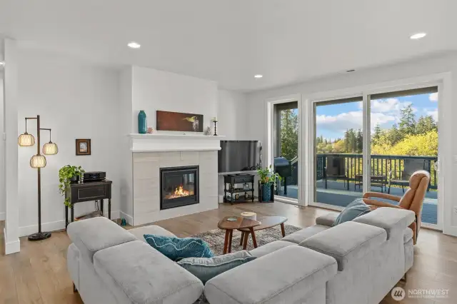 A modern gas fireplace anchors the airy living area, offering cozy ambiance while maintaining an open connection to the kitchen and dining space.