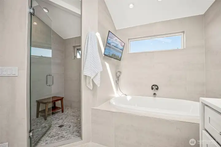 Separate tub and shower of primary suite. Yes, that is a mounted tv for you to enjoy while taking a bath!! This shower also has 'smart features' so that you can program the temperature and other settings you prefer.