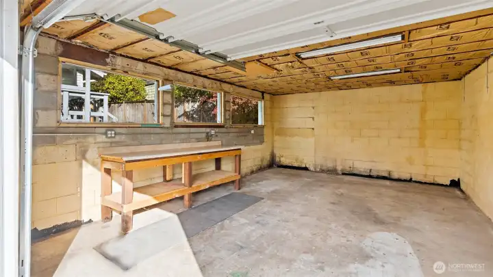 That’s right - multiple outlets, a sturdy workbench, and plenty of overhead lighting make this a great spot for projects or hobbies. Three large windows overlook the backyard, filling the space with natural light and making it feel bright and inviting all day long.