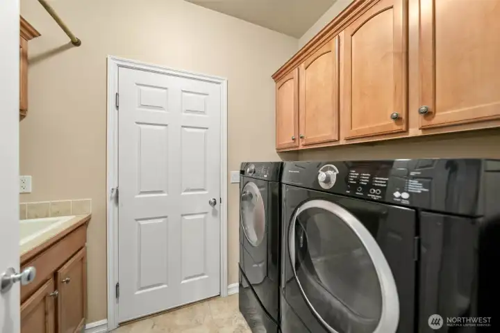 Laundry room entry from the garage with ample storage and a utility sink.