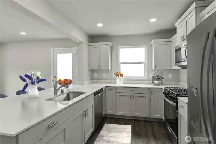 Photo is for Light-filled kitchen featuring quartz countertops, stainless steel appliances, and a spacious center island