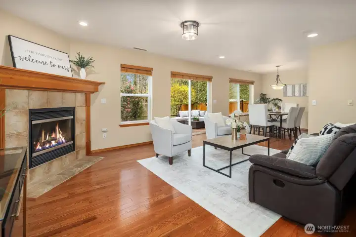 The warm and inviting living room features rich hardwood floors, designer paint, and a cozy fireplace with a classic surround that serves as a natural focal point for the space. Bathed in natural light and thoughtfully designed for both relaxed everyday living and easy entertaining, this comfortable gathering space flows beautifully into the adjacent areas of the main level.