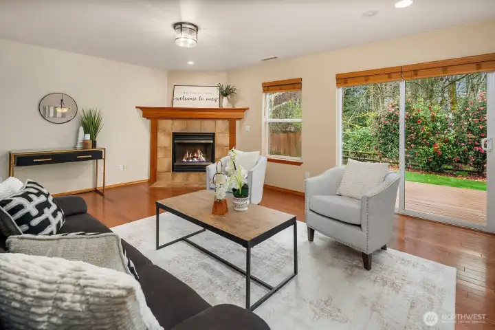 This beautifully lit view of the living room highlights the large windows that flood the space with warm natural light, perfectly complementing the rich hardwood floors, cozy fireplace, and designer finishes throughout. The generous layout and effortless flow of this inviting space make it the ideal setting for both quiet relaxation and lively gatherings with family and friends.
