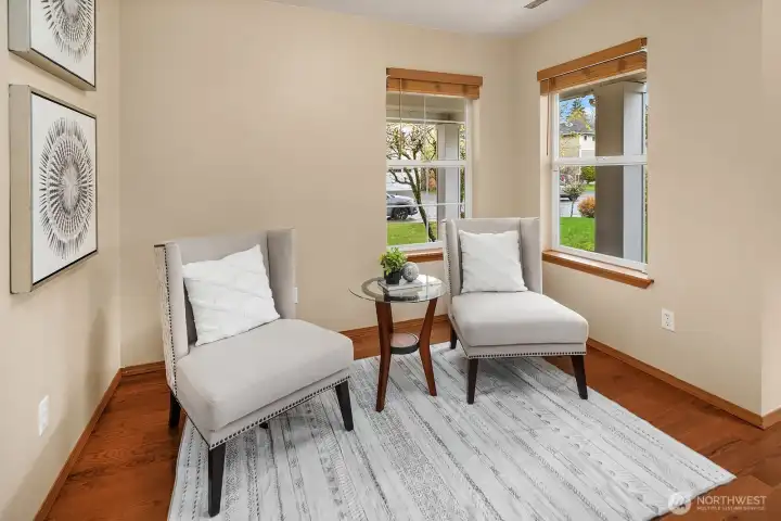 This charming alternate view of the main level flex space highlights the warm natural light streaming through the large window, rich hardwood floors, and the inviting, intimate atmosphere that makes this room such a versatile and welcome addition to the home. Whether styled as a quiet reading retreat, home office, or formal sitting room, this beautifully finished space adapts effortlessly to any lifestyle need.