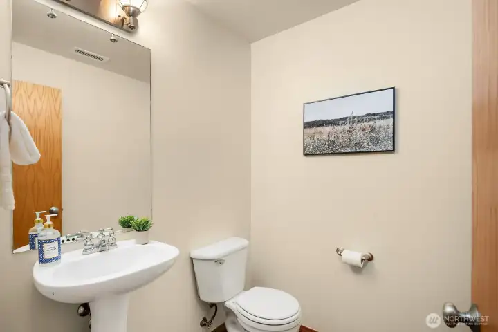 This clean and conveniently located main level powder room features a classic pedestal sink and fresh neutral finishes that provide guests with a functional and tidy space. Simple and well-maintained, this practical half bath is a welcome amenity on the main level for everyday living and entertaining alike.