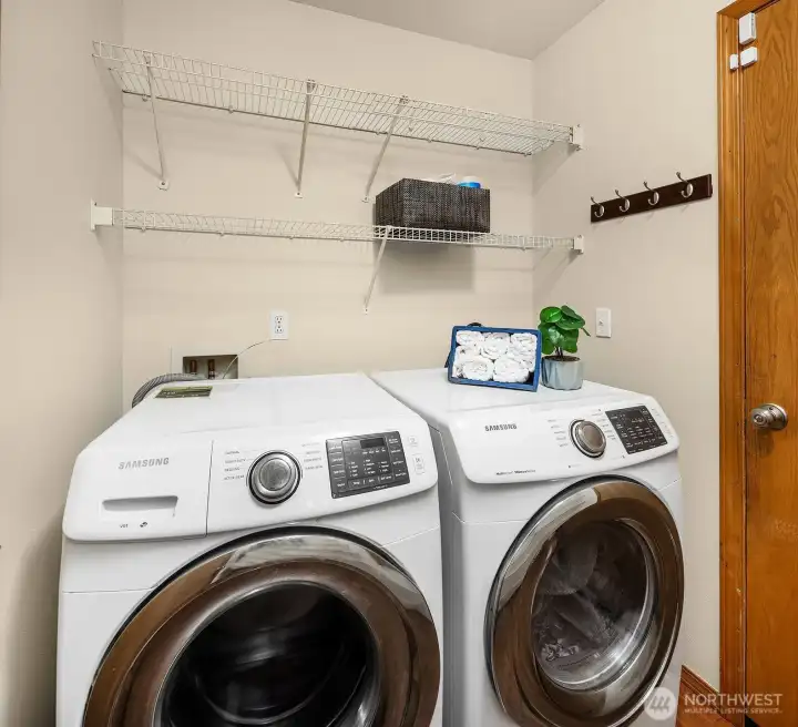 This conveniently located laundry area features a full-size front-loading washer and dryer along with overhead shelving that maximizes storage in a compact and efficient space. Practical and move-in ready, this well-organized laundry setup adds to the everyday functionality and convenience that this thoughtfully designed home delivers throughout.