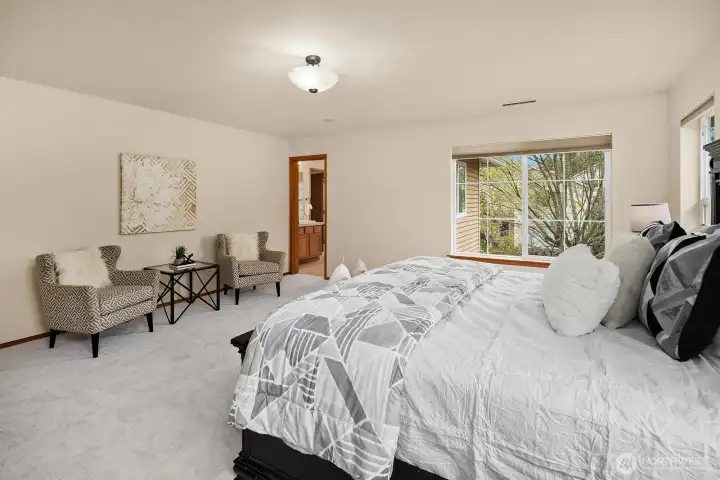 Another angle of the primary suite highlighting the spacious layout with room for a sitting area, and a glimpse into the walk-in closet beyond — comfort and functionality beautifully combined.