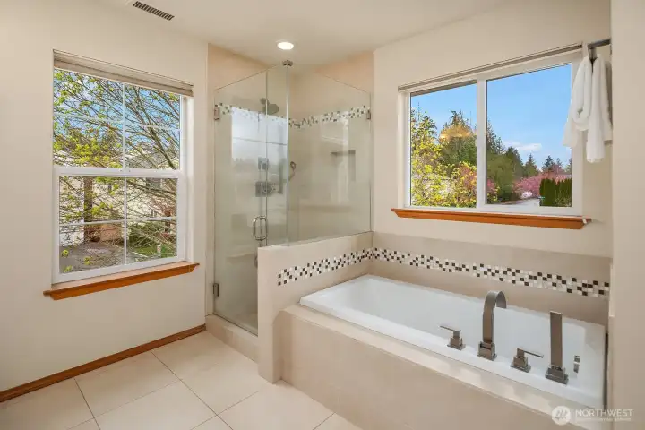 A closer look at the spa-inspired bath showcasing the full-length glass shower door and elegant sunken soaking tub framed by beautiful windows — the perfect setting to relax and recharge.