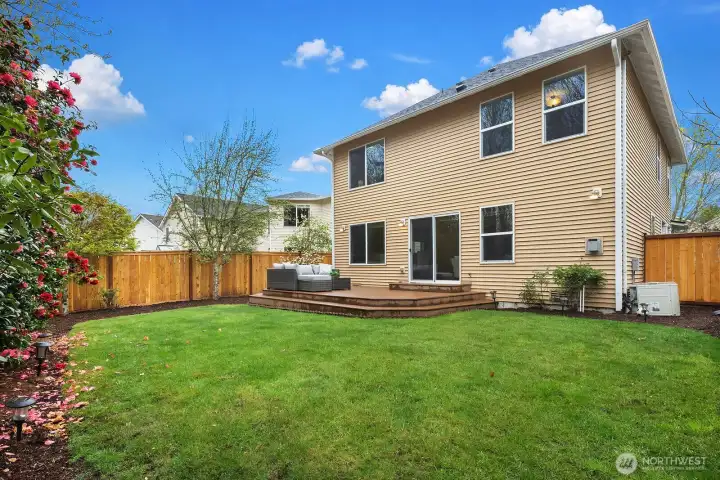 Enjoy the outdoors in this lovely fully fenced backyard featuring a wood deck patio, lush green lawn, and mature trees — backing to natural open space for added privacy and tranquility.