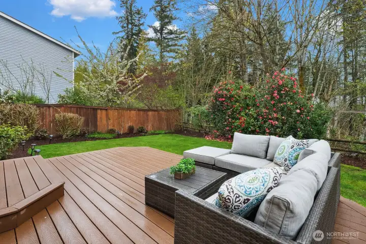 Another angle of the inviting deck showcasing the generous entertaining space, stylish outdoor seating, and the lush natural backdrop — seamlessly blending indoor comfort with outdoor living.