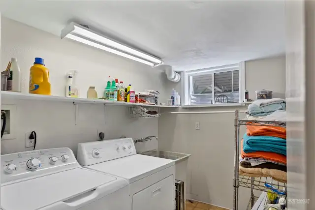 The lower-level laundry room offers extra storage and a utility sink. This is located next to the stairwell, and the sump pump is located under the stairs to the right of this picture.